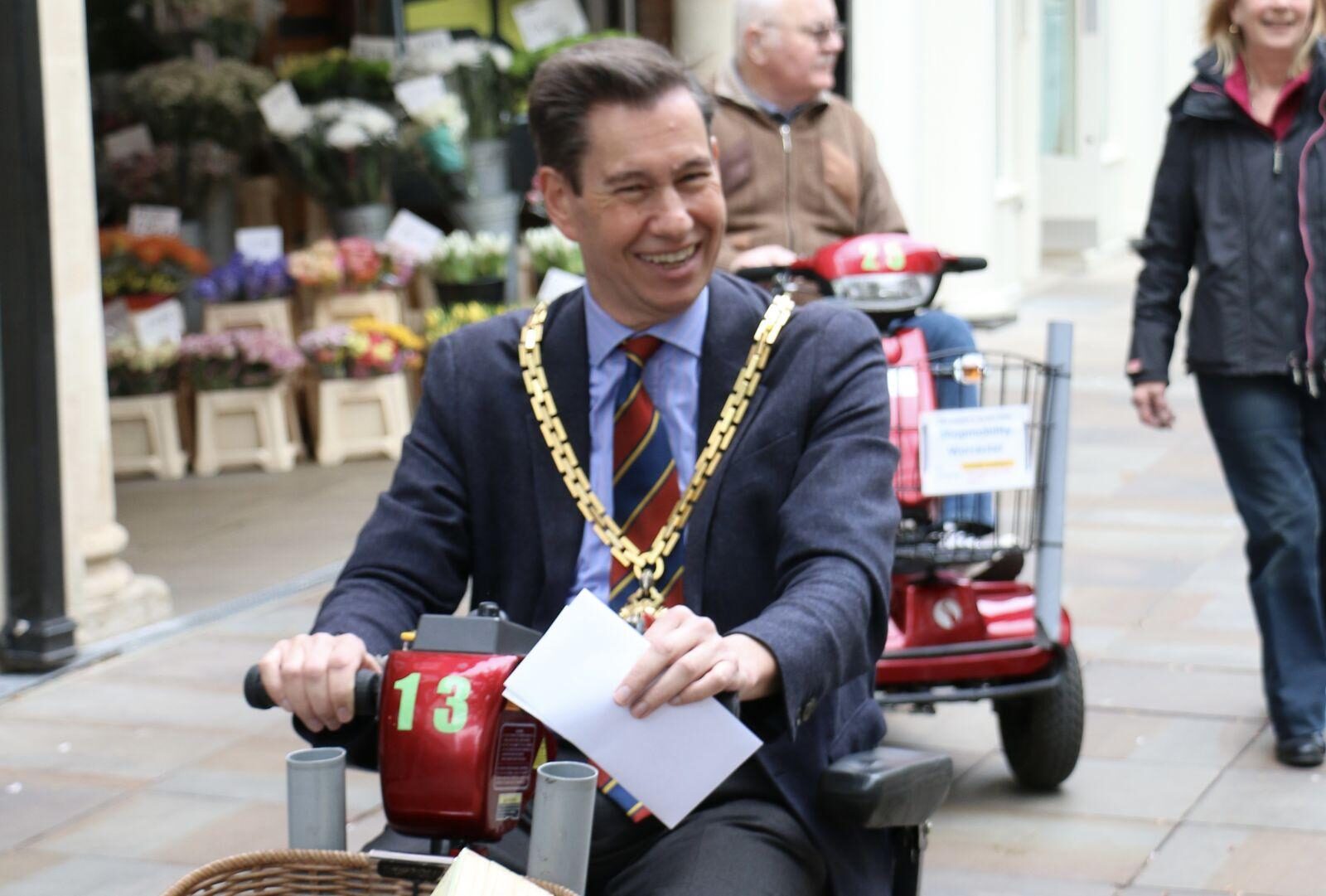 Mayor riding on ShopMobility scooter through Worcester high street